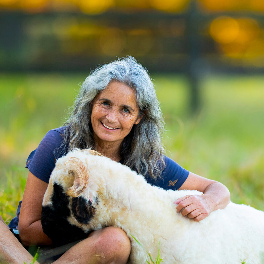 Noeline Cassetari, a woman with silver hair, pictured with a white and black sheep.